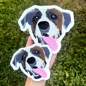 Puede incluir: Dos parches bordados con la cara de un perro con la lengua rosa. El perro tiene pelo marrón, negro y blanco. Los parches están delineados en blanco y son de diferentes tamaños. El fondo es hierba verde.