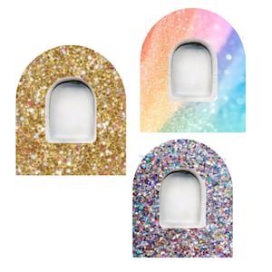 May include: Three nail art designs. One is gold glitter, another is a rainbow gradient, and the third is silver glitter. Each design has a white, arched space for the nail.