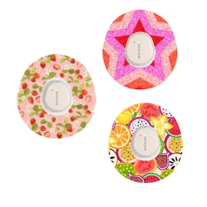 May include: Three Dexcom G6 sensor covers with different designs. One features strawberries on a pink background, another a star pattern in shades of pink and red, and the third a colorful fruit pattern.