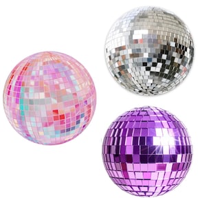 May include: Three spherical disco balls featuring a reflective surface made of small square mirror tiles. One ball is iridescent pink, one is silver, and one is a solid deep purple colour. Each ball is designed to reflect light from all angles.