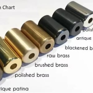 May include: A finish chart displaying cylindrical metal objects in various finishes, including antique patina, polished brass, brushed brass, raw brass, blackened brass, antique black, and polished chrome. The text "Finish Chart" is at the top.