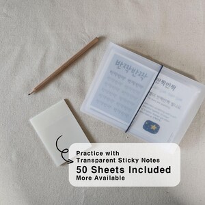 May include: A set of transparent sticky notes in a frosted plastic case secured with a black elastic band, accompanied by a single wooden pencil. The case contains cards with Korean text reading "반짝반짝" and a small illustration of a yellow star.