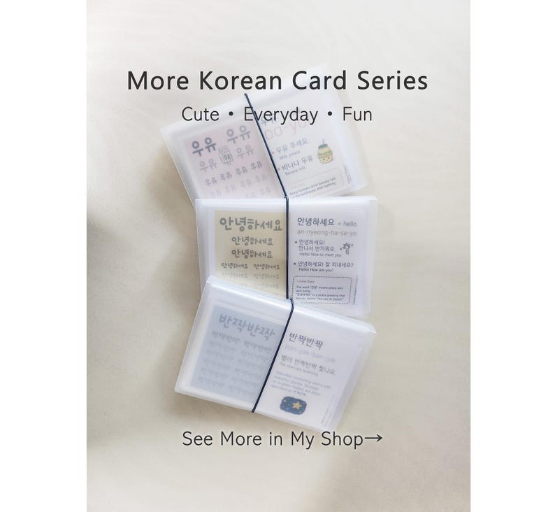 May include: A set of three translucent plastic cases containing Korean language learning cards, stacked vertically and secured with a black elastic band. Each card features Korean text, English translations, and illustrations.