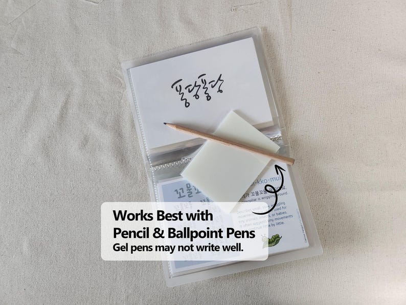 May include: A clear plastic card holder containing white cards with Korean text and a small wooden pencil resting on a translucent white square note. The text on the overlay reads: Works Best with Pencil & Ballpoint Pens. Gel pens may not write well.