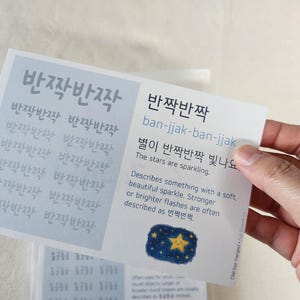 May include: A rectangular educational card with a light blue section on the left featuring the Korean text ban-jjak-ban-jjak repeated. The right side defines the term with English text, phonetic spelling, and a small illustration of a yellow star.