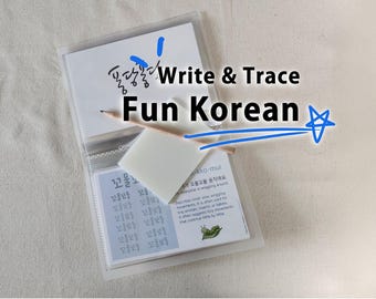 May include: A clear plastic binder containing educational cards for learning Korean, featuring the text Write & Trace Fun Korean. A wooden pencil rests on top of a white rectangular eraser placed over the cards, which display Korean characters.