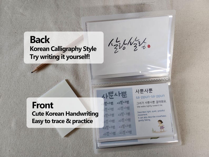 May include: A clear plastic card holder containing instructional cards for learning Korean calligraphy. The cards feature the text '살랑살랑' and '사뿐사뿐' with definitions and practice grids. A wooden pencil and a stack of translucent sticky notes are included.