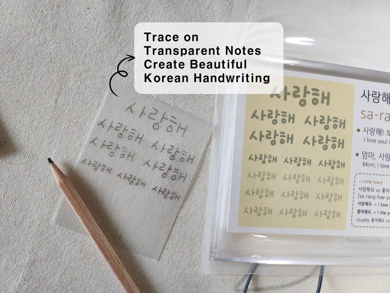May include: A wooden pencil resting on a square piece of transparent paper featuring the Korean text "사랑해" repeated in rows. Next to it is a clear plastic sleeve containing a yellow sheet with printed Korean characters and English definitions.