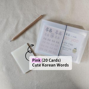 May include: A set of twenty pink Korean vocabulary cards housed in a translucent frosted plastic case with a black elastic band closure, accompanied by a wooden pencil and a small matching translucent plastic card holder.