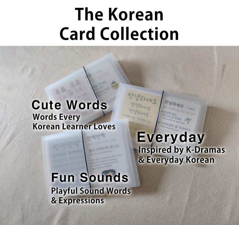 May include: Three sets of rectangular flashcards in translucent frosted plastic cases, each secured with a thin black elastic band. The cards feature Korean text, English translations, and phonetic pronunciations, labeled as Cute Words, Everyday, and Fun Sounds.
