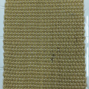 Puede incluir: Alfombra rectangular tejida en color marrón claro natural con un borde gris oscuro. La alfombra presenta una superficie texturizada con un patrón repetitivo de fibras entrelazadas. Mide aproximadamente 100 cm x 60 cm, adecuada para uso interior o exterior.