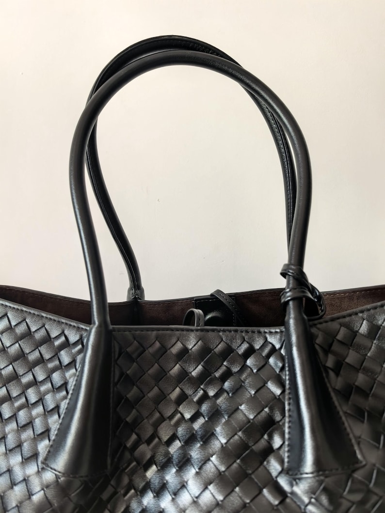 Top handle detail of black woven leather tote bag with smooth leather straps