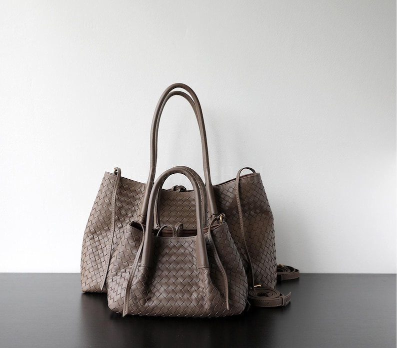 Puede incluir: Dos bolsos de mano de cuero tejido en color topo neutro. El bolso m&aacute;s grande tiene asas altas y una correa para el hombro, mientras que el bolso m&aacute;s peque&ntilde;o tiene asas m&aacute;s cortas. Ambos bolsos tienen un dise&ntilde;o tejido.