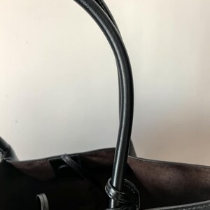 Close-up of leather handle attachment on black braided tote bag