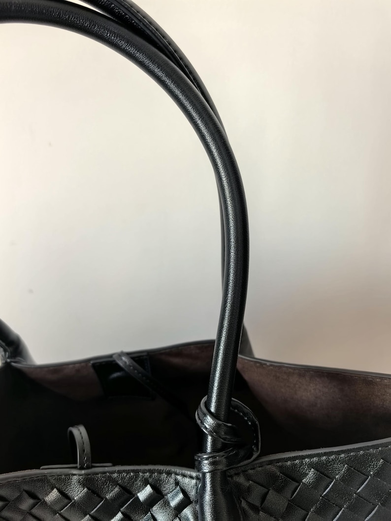 Close-up of leather handle attachment on black braided tote bag