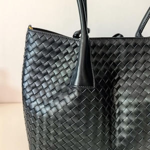Close-up of black braided leather tote bag showing woven texture detail