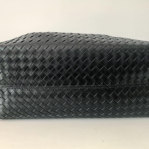 Puede incluir: Bolso tote de cuero negro con un dise&ntilde;o tejido en forma de cesta. El bolso tiene forma rectangular y una base robusta. El cuero parece liso y el tejido est&aacute; bien construido.