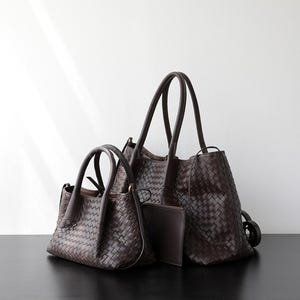 Puede incluir: Tres bolsos de mano de cuero marr&oacute;n de diferentes tama&ntilde;os se muestran sobre un fondo blanco. Los bolsos tienen texturas tejidas y asas resistentes. Tambi&eacute;n hay un peque&ntilde;o embrague. Los bolsos est&aacute;n sobre una superficie negra.