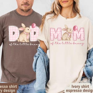May include: Two t-shirts, one espresso and one ivory, feature a bunny graphic with the text "DAD of the little bunny" and "MOM of the little bunny". The bunny is wearing a pink bow tie and holding a pink balloon. The shirts are a casual style.
