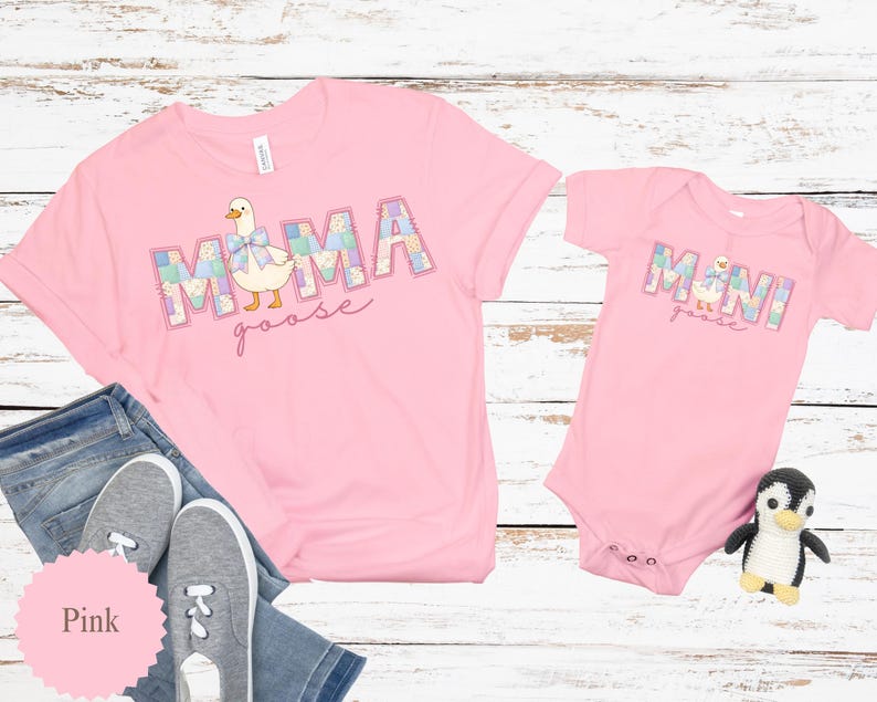 K&ouml;nnte beinhalten: Rosafarbene T-Shirts und ein Baby-Body mit einem "MAMA goose" und "MINI goose" Design. Der Text ist im Patchwork-Stil mit einer Cartoon-Gans-Illustration gehalten. Ein Paar graue Turnschuhe und ein Pinguin-Pl&uuml;schtier sind ebenfalls im Bild.