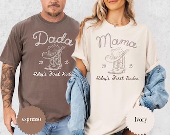 May include: Two t-shirts, one espresso and one ivory, featuring a cowboy hat and boots design. The espresso shirt says "Dada" and the ivory shirt says "Mama". Both shirts have the text "Riley's First Rodeo" and the numbers "20 25".