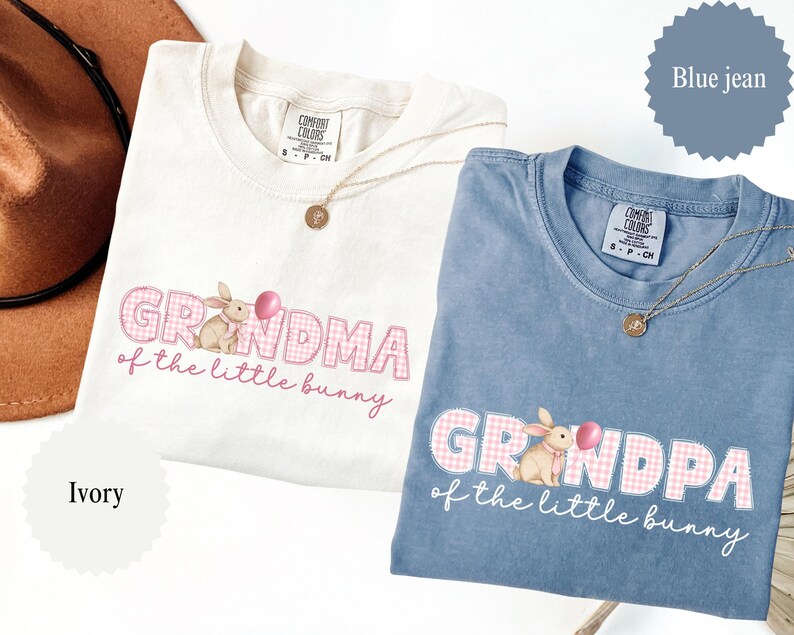May include: Two Comfort Colors t-shirts, one ivory and one blue jean, featuring the text "Grandma of the little bunny" and "Grandpa of the little bunny" with a bunny graphic. Each shirt has a gold necklace.