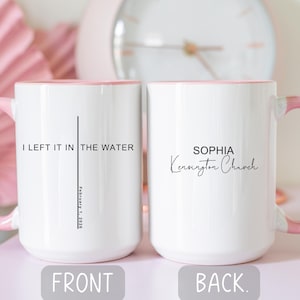 May include: Two white ceramic mugs with pink handles and rims. One mug has the text "I LEFT IT IN THE WATER" with a vertical line and the date "February 1, 2026". The other mug has the name "SOPHIA" and "Kensington Church".