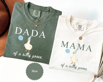 May include: Two Comfort Colors t-shirts, one moss green and one cream, with the words "DADA" and "MAMA" printed on them. Each shirt features a cartoon goose holding a balloon and wearing a party hat. The phrase "of a silly goose" is printed below.