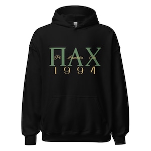 May include: Black hooded sweatshirt with the Greek letters ΠΛΧ and the year 1994 printed in green and gold. The sweatshirt has a drawstring hood and a front pocket.