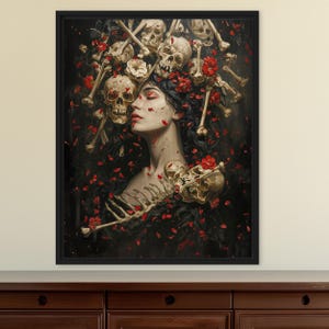 May include: A framed wall art print featuring a profile portrait of a person with dark hair surrounded by scattered human skulls, bones, and vibrant red flower petals against a dark background. The composition includes skeletal elements.