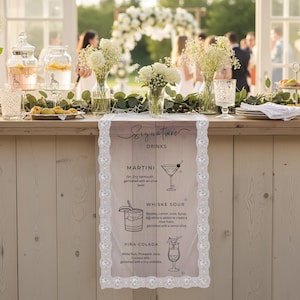May include: A rectangular table runner with a white lace border featuring a printed menu titled Signature Drinks. The text lists Martini, Whiskey Sour, and Pi&ntilde;a Colada with corresponding line art illustrations of each cocktail glass on a light background.