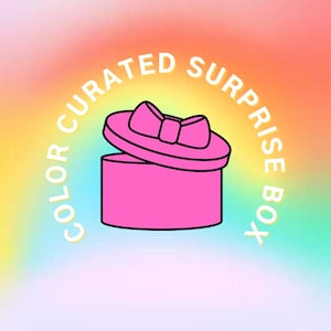 May include: A pink gift box with a bow on the lid, set against a colorful gradient background. The text "COLOR CURATED SURPRISE BOX" is arched around the box in white letters. The box is open, suggesting a reveal.