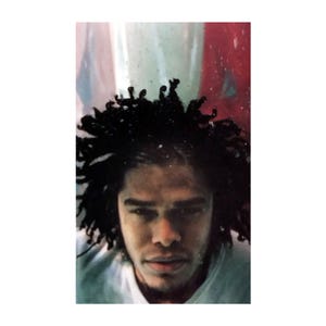 May include: A portrait of a person with dark skin and black dreadlocks. The person is looking directly at the viewer. The background is a mix of red, white, and blue.