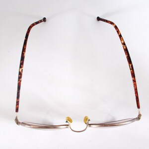 May include: Eyeglasses with a silver frame and tortoise shell arms. The glasses have a classic design with a curved browline and nose pads. The arms are a dark brown with lighter brown and tan spots.