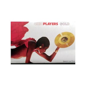 May include: Album cover for Ohio Players' "Gold" featuring a person holding a gold record. The image has a red and white color scheme with the text "OHIOPLAYERS GOLD" at the top. The words "Special Low Price" are at the bottom.