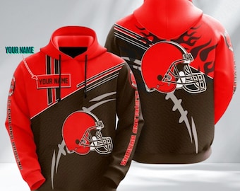 May include: A red and brown hooded sweatshirt featuring a Cleveland Browns football helmet graphic, black stripes, and a rectangular box with the text YOUR NAME. The design includes flame patterns on the back and the text CLEVELAND BROWNS.