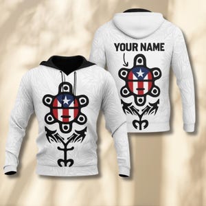 May include: White hoodie with a black-lined hood and a design featuring a Puerto Rican flag motif. The front and back of the hoodie display a stylized emblem with the text "YOUR NAME" on the back. The design includes a star, stripes, and a unique tribal pattern.