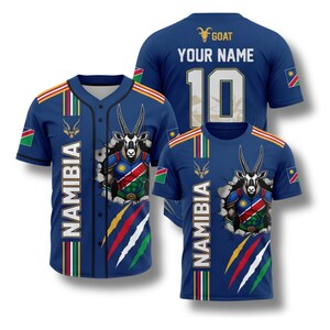 Peut inclure: Trois chemises bleues sur le thème de la Namibie. L'une est un maillot de baseball, et deux sont des t-shirts. Chacune présente un graphisme d'un oryx perçant un mur, le mot "NAMIBIA" et les couleurs du drapeau namibien.