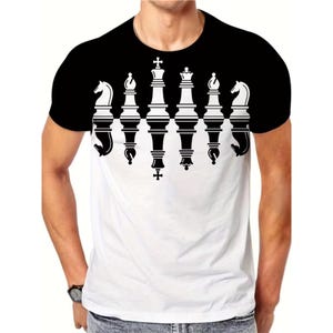以下が含まれることがあります： チェスのデザインが施された白と黒のTシャツ。Tシャツの上部は黒で、胸元で白に変わります。デザインには、縦に配置されたチェスの駒が含まれています。