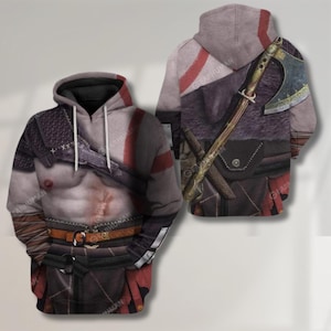Puede incluir: Una sudadera con capucha gris con una impresión detallada del torso de un guerrero, con cicatrices de batalla, armadura y un cinturón. La parte trasera de la sudadera muestra un hacha grande y una capa forrada de piel, con rayas rojas.