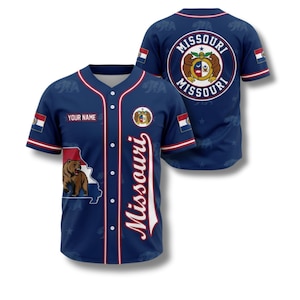 May include: A navy blue baseball jersey featuring the Missouri state outline with a bear graphic. The jersey includes the word "Missouri" in white script, a Missouri state seal, and the option to add a name. The sleeves have red and white accents.