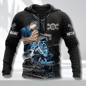 Könnte beinhalten: Schwarzer Kapuzenpullover mit einem Mechaniker, der an einem Motor arbeitet. Das Design zeigt die Wörter "NAME" auf dem linken Ärmel und "MECH" auf dem rechten Ärmel. Der Hintergrund hat ein Riffelblechmuster.