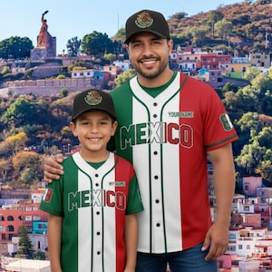 May include: Two people wearing matching baseball jerseys and caps with the word "MEXICO" on the front. The jerseys feature the colors of the Mexican flag: green, white, and red. The caps have a Mexican coat of arms.