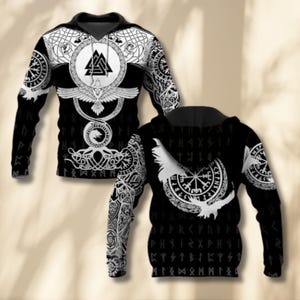 May include: Black hoodie with white Norse-inspired patterns. The front displays a central emblem with a triangle, bird, and circular designs. Sleeves and back are decorated with runes and symbols. The design is intricate and detailed.