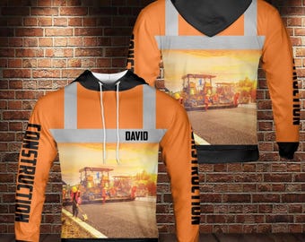 May include: An orange construction hoodie with a black hood and cuffs. The design includes reflective stripes and the word "CONSTRUCTION" printed vertically on the sleeves. The front displays a construction scene and the name "DAVID".