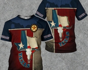Op de afbeelding: Een T-shirt met korte mouwen met een Texas-thema. Het ontwerp toont de vlag van Texas, een schedel van een longhorn en het woord "TEXAS". Het ontwerp gebruikt de kleuren rood, wit, blauw en bruin. Het woord "NAME" staat op de mouwen.