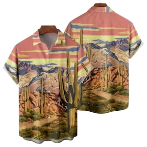 May include: Short-sleeved button-down shirt featuring a desert landscape design. The shirt showcases a scenic view with cacti, mountains, and a sunset in shades of orange, yellow, and blue. The shirt is displayed on a hanger.