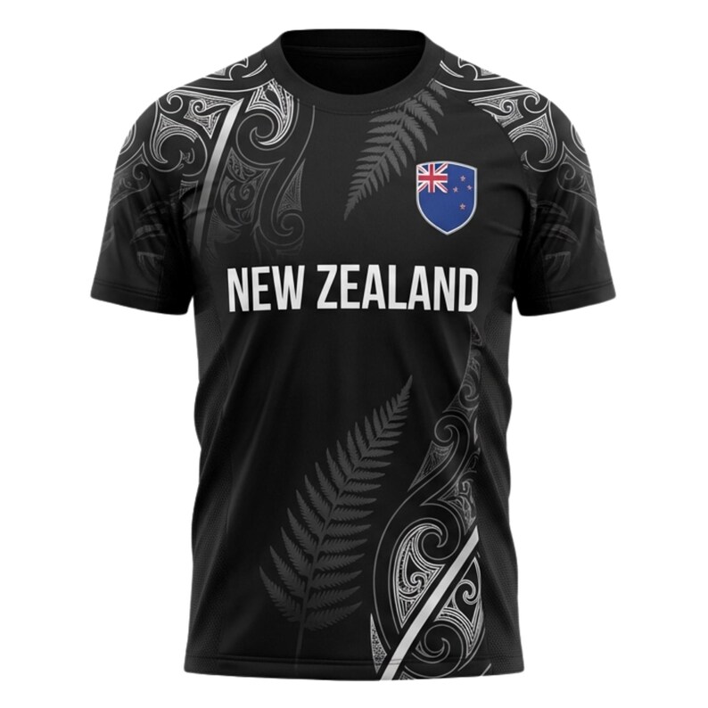 May include: Black t-shirt with white text that reads "NEW ZEALAND". The shirt features a fern design and a New Zealand flag emblem. The shirt has a crew neck and short sleeves.