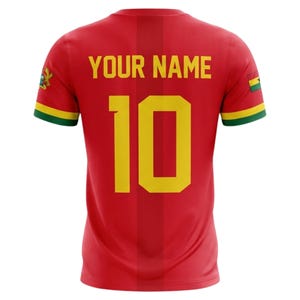 May include: Red soccer jersey with the number 10 in yellow, and the text "YOUR NAME" above it. The jersey has green and yellow accents on the sleeves and the Ghana flag on the sleeves.