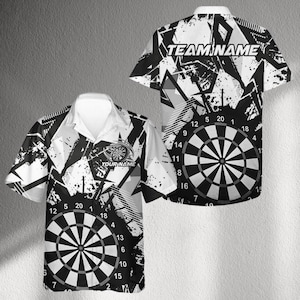 May include: Short-sleeved shirt featuring a dartboard design. The shirt is black and white with geometric shapes and a dartboard graphic on the front and back. The text "YOUR NAME" and "TEAM NAME" are visible.